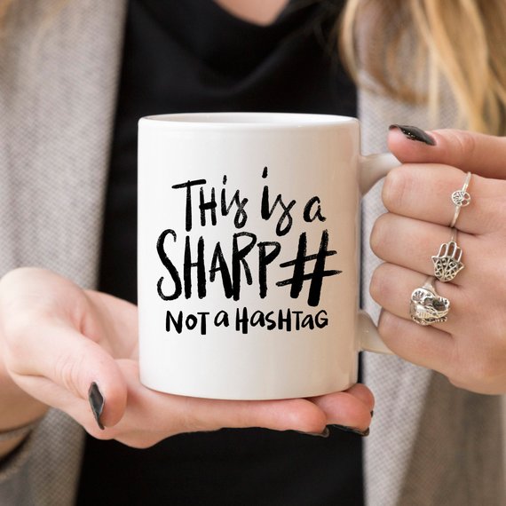 A humorous coffee mug with the phrase 'This Is A Sharp, Not A Hashtag' printed on it, showcasing a playful design suitable for coffee lovers.