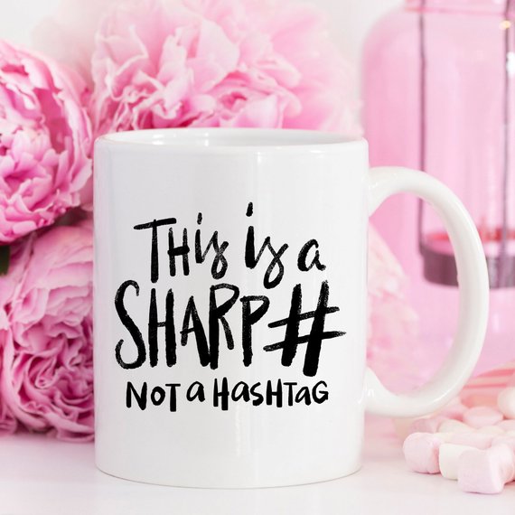 A humorous coffee mug with the phrase 'This Is A Sharp, Not A Hashtag' printed on it, showcasing a playful design suitable for coffee lovers.