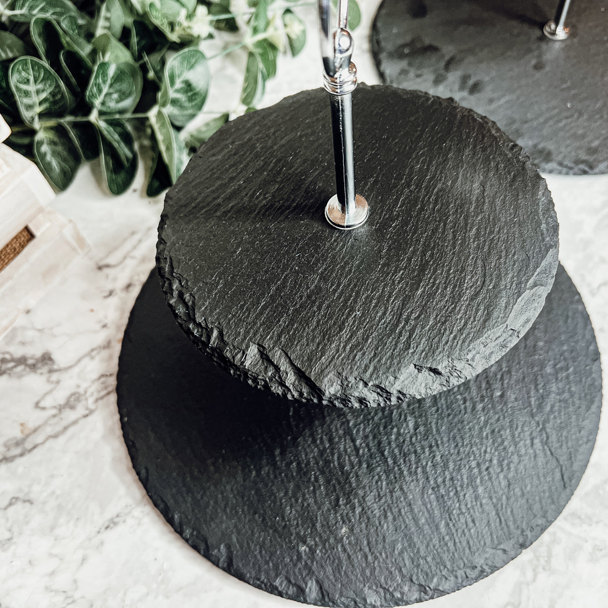 A stylish tiered slate stand showcasing appetizers and desserts, featuring natural edges and a modern design.