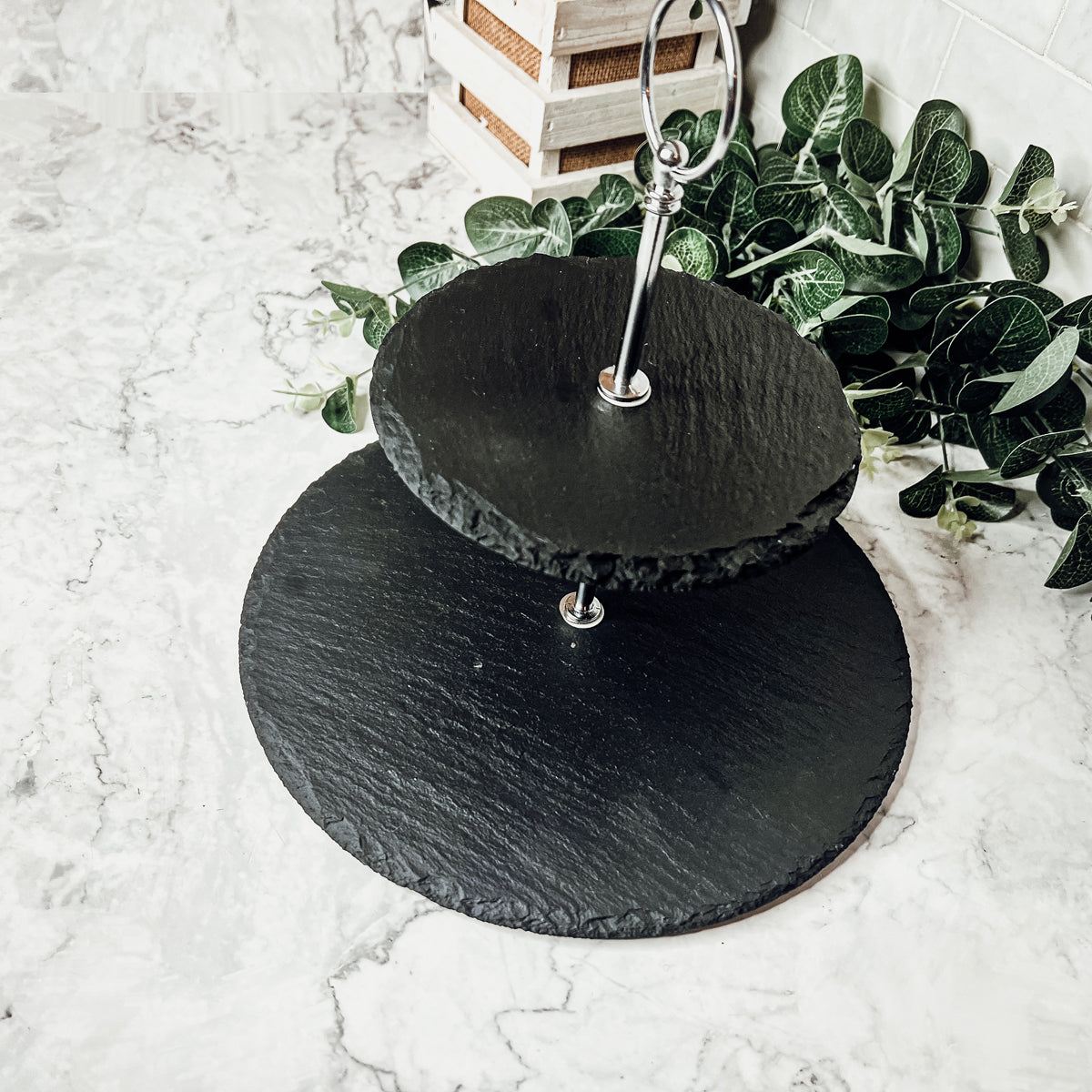 A stylish tiered slate stand showcasing appetizers and desserts, featuring natural edges and a modern design.