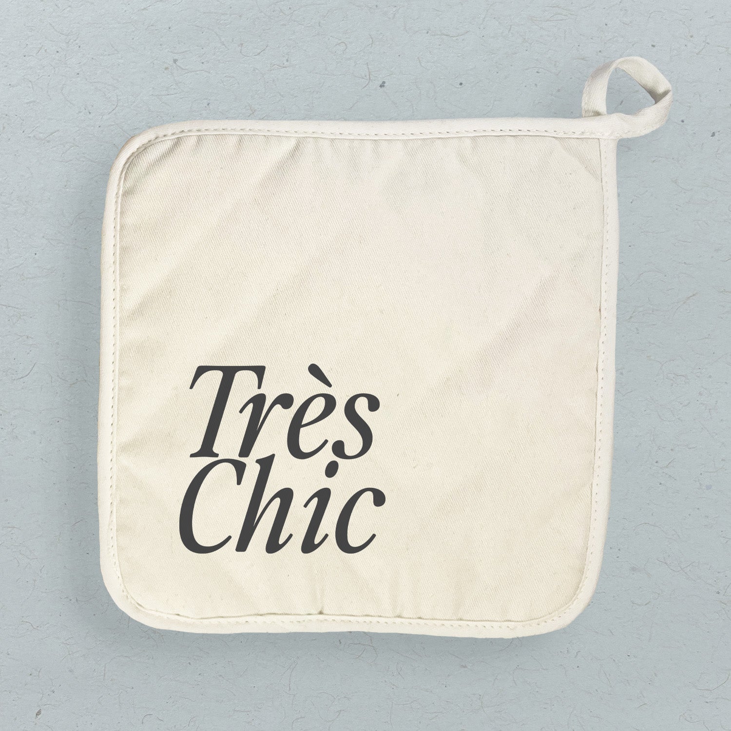 Tres Chic Cotton Pot Holder featuring vibrant designs and a convenient hanging loop, perfect for protecting surfaces from hot cookware.