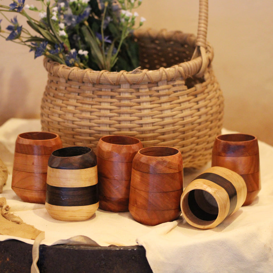 Artisan wooden tumbler made from walnut, cherry, and maple, showcasing unique wood grains and a food-safe finish.