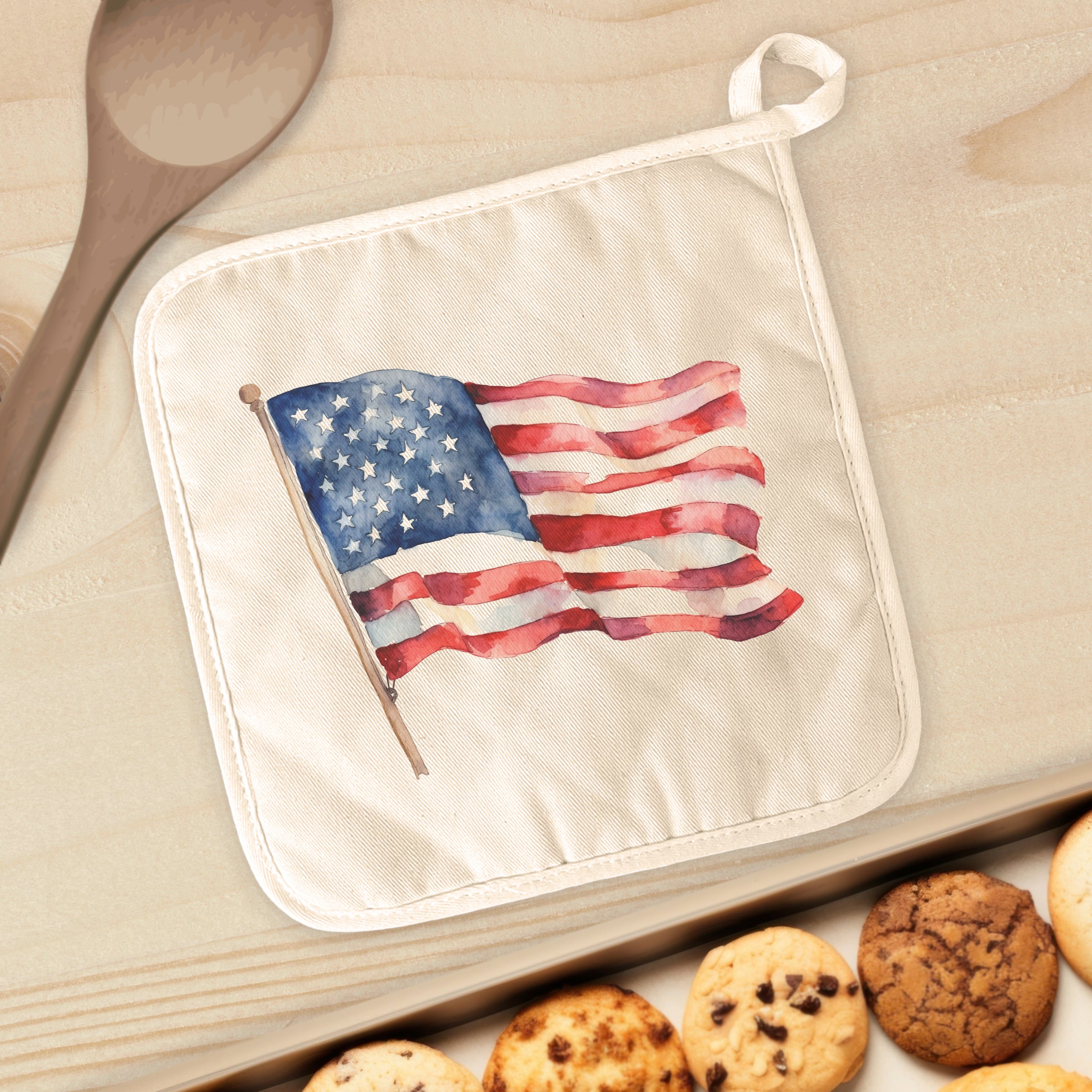 A vibrant watercolor American flag pot holder made of cotton and terry cloth, featuring a convenient hanging loop and quilted design.