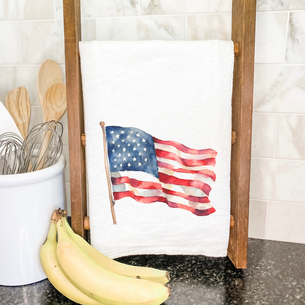 A vibrant watercolor American flag design on a cotton tea towel, showcasing its hemmed edges and absorbent texture.