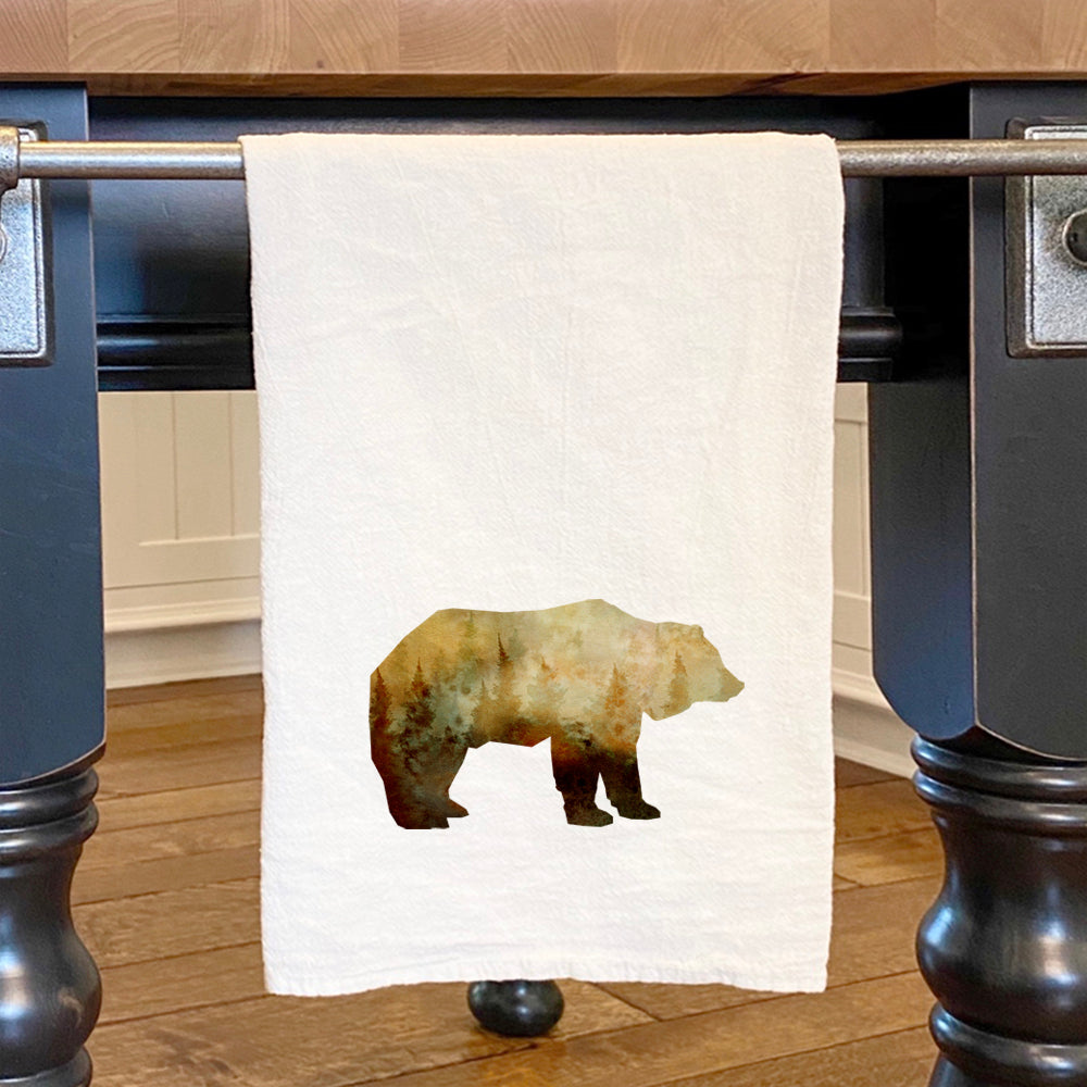 A vibrant cotton tea towel featuring a watercolor bear design, showcasing its absorbent texture and hemmed edges.