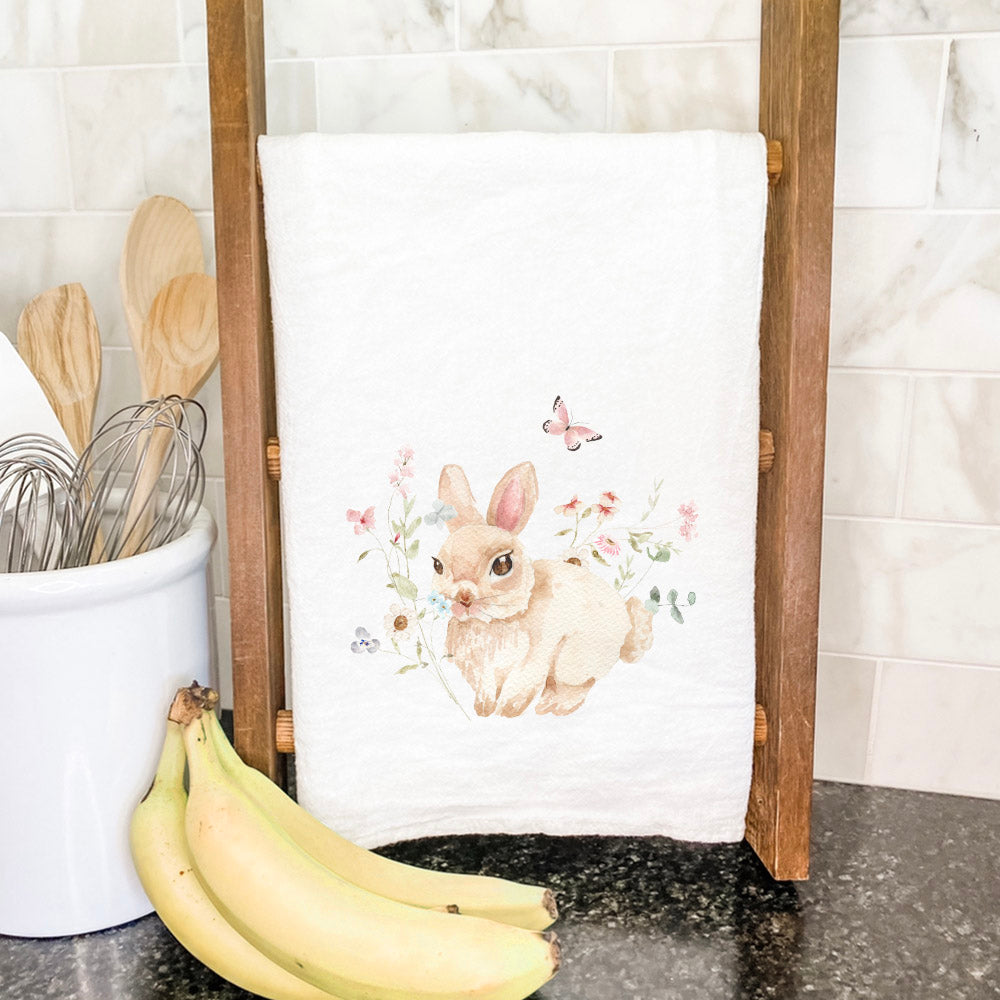 A vibrant cotton tea towel featuring a watercolor bunny surrounded by colorful florals, perfect for kitchen use.