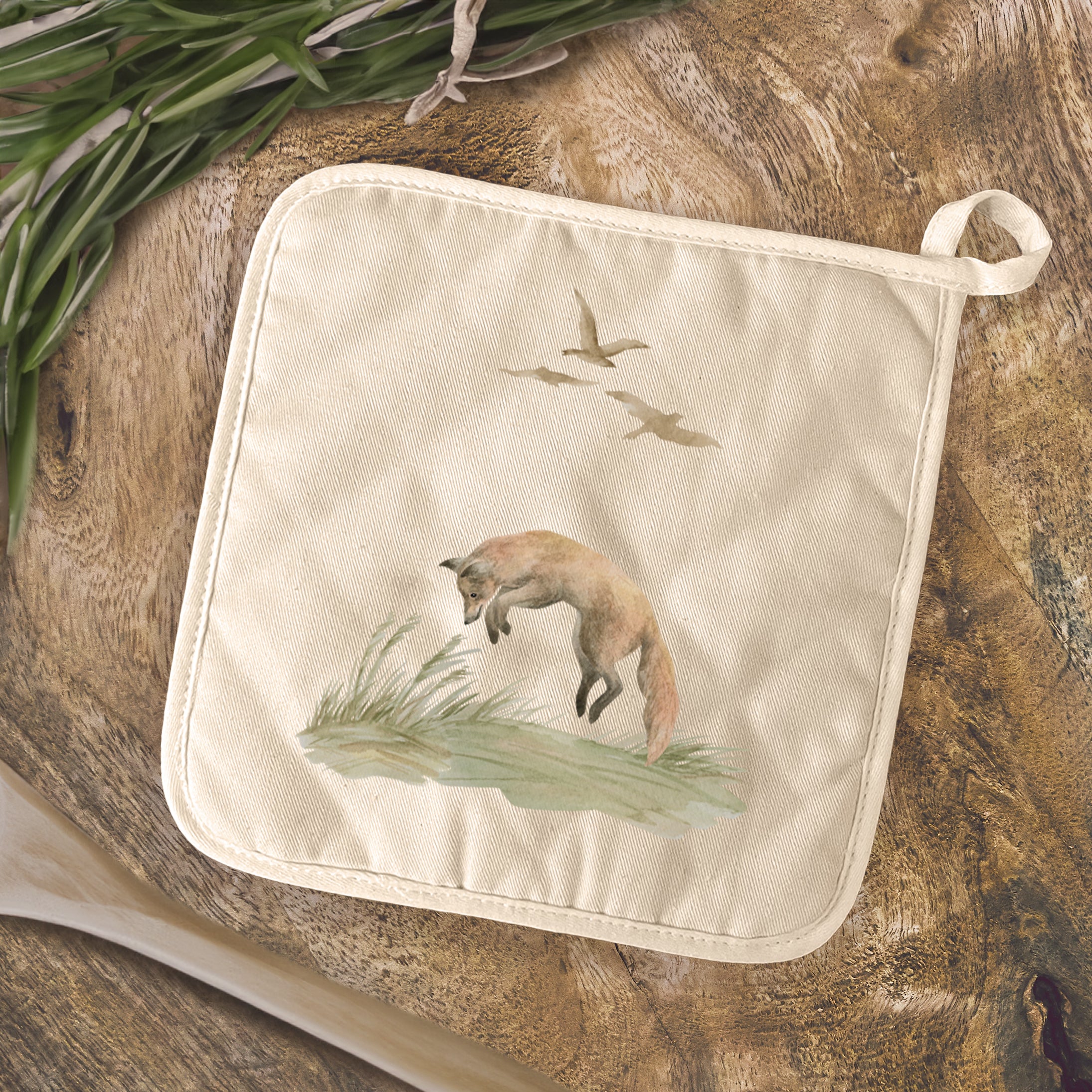 A square cotton pot holder featuring a vibrant watercolor fox design, perfect for protecting surfaces from hot cookware.