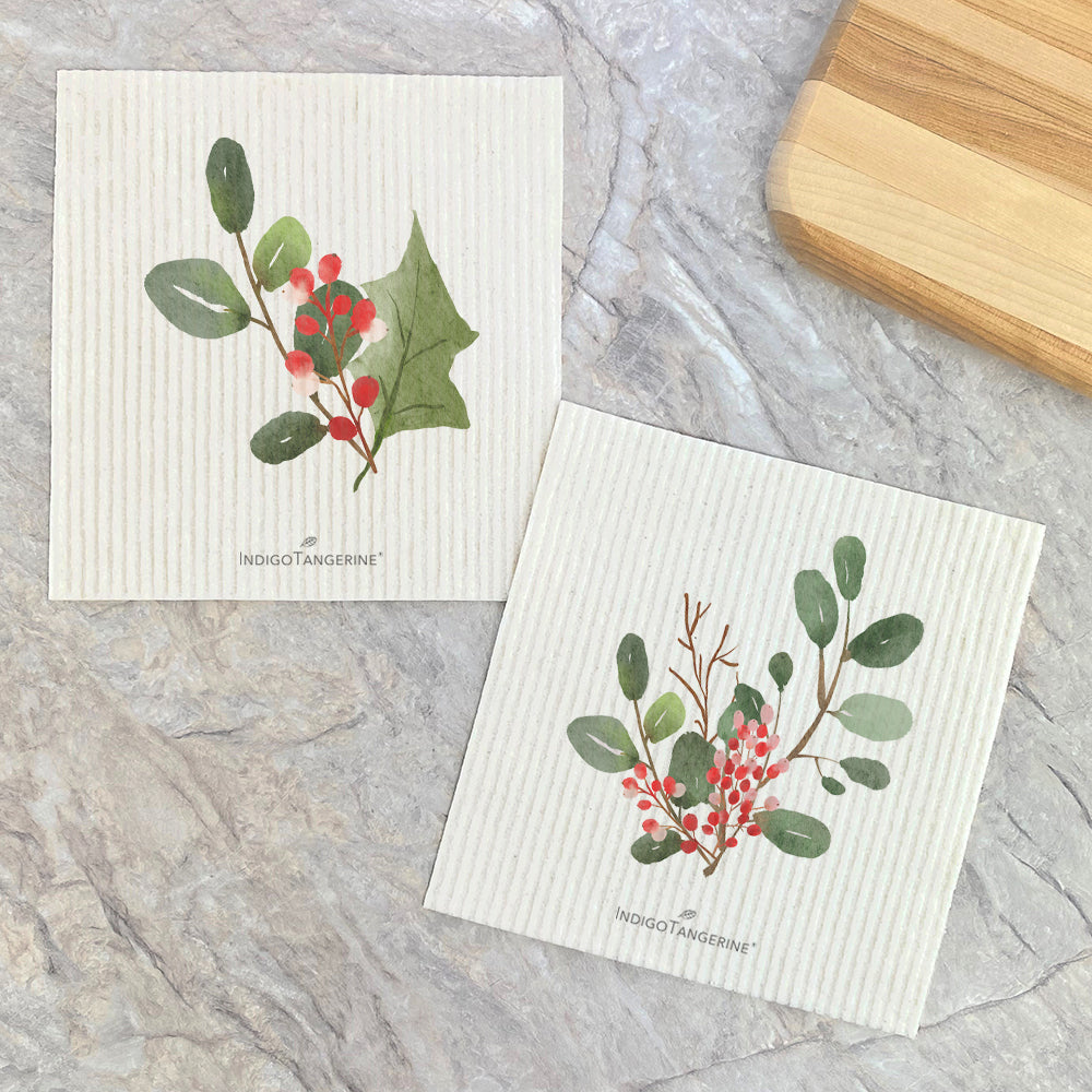 Two eco-friendly Swedish dish cloths featuring a watercolor holly branch design, showcasing vibrant colors and a natural texture.