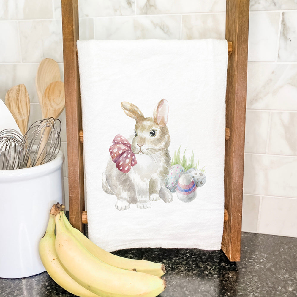 A beautifully designed cotton tea towel featuring a watercolor rabbit surrounded by colorful eggs, perfect for kitchen decor.