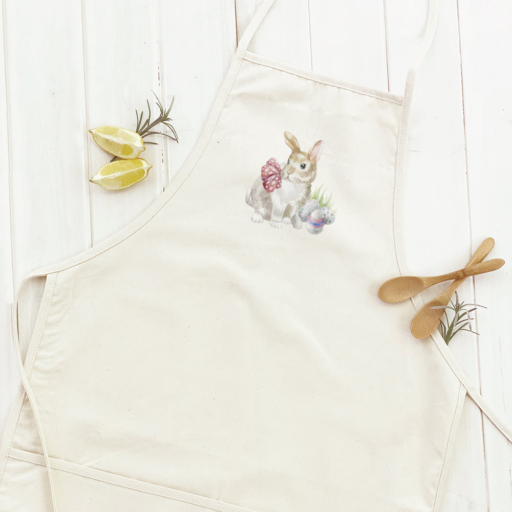 A stylish women's apron featuring a watercolor rabbit design with colorful eggs, made from durable cotton canvas with adjustable neck and twill ties.