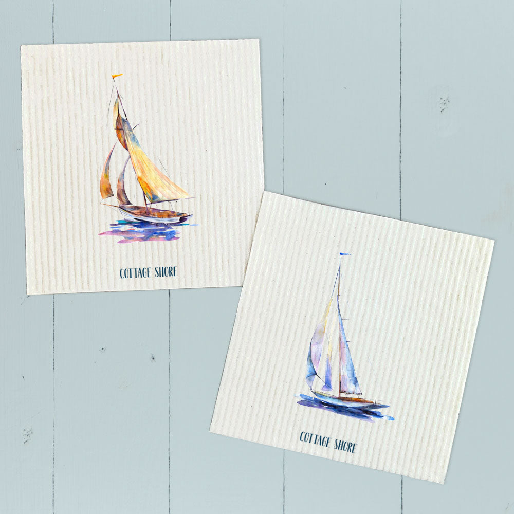 Two Swedish dish cloths featuring watercolor sailboat designs in orange and blue, made from eco-friendly materials.