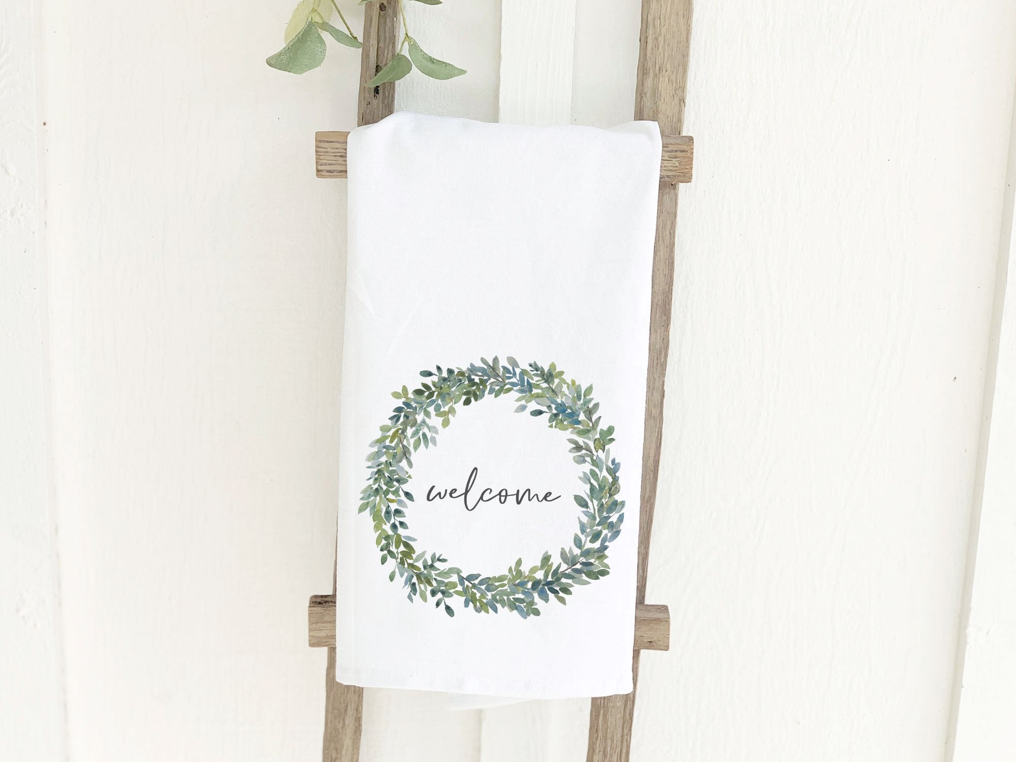 Welcome Boxwood Wreath cotton tea towel featuring a vibrant boxwood wreath design on a white background.