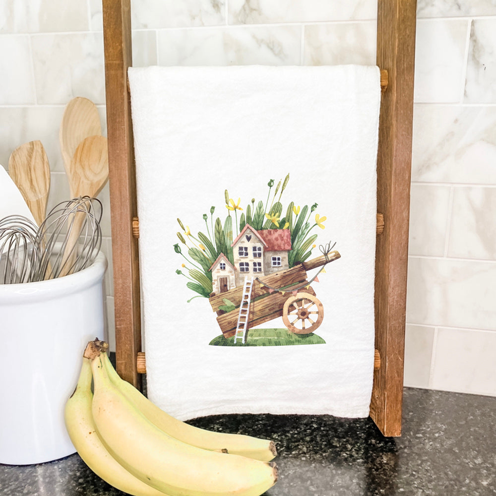 A charming cotton tea towel featuring a whimsical Wheelbarrow Fairy House design, perfect for kitchen use.