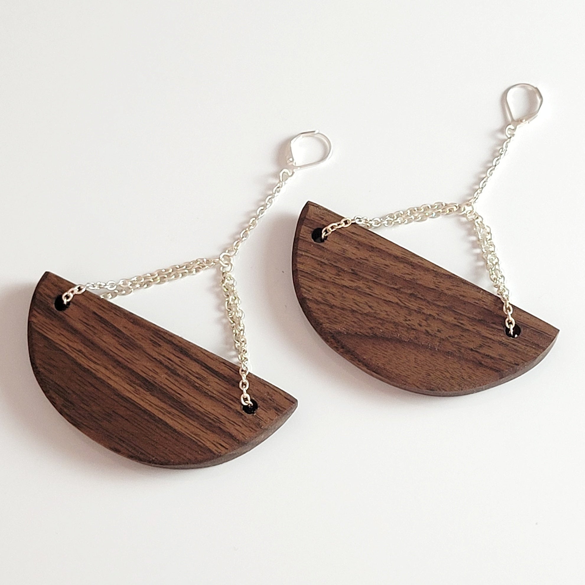 Handmade wooden half-moon earrings with silver plated attachments, showcasing cherry and walnut wood options.