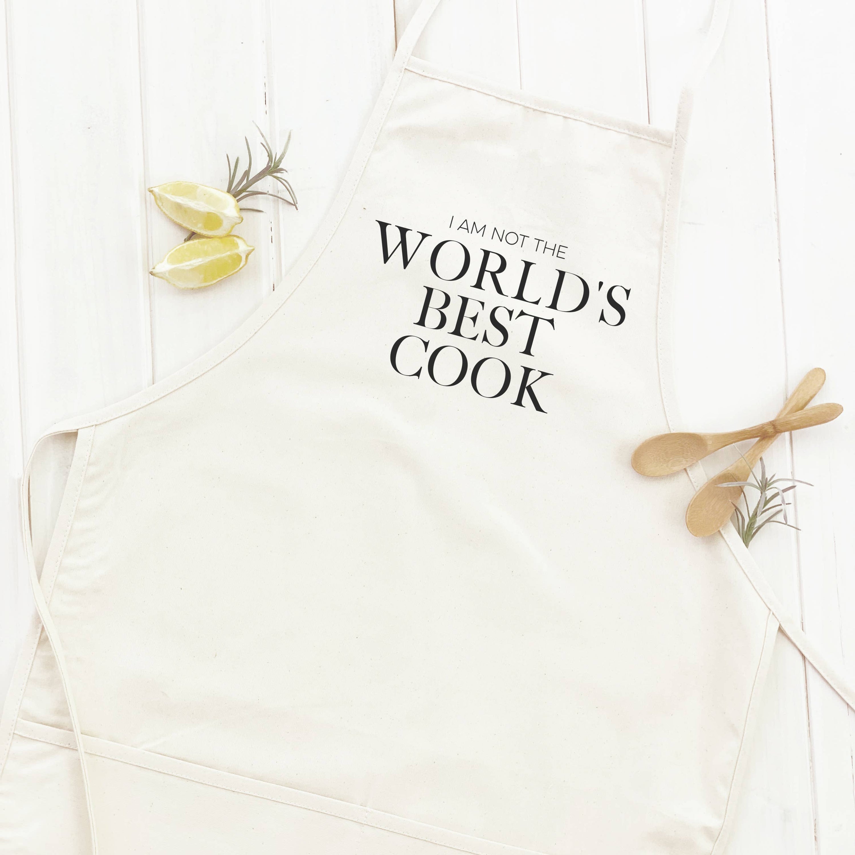 Stylish women's apron with 'World's Best Cook (NOT)' print, featuring natural twill ties and a divided front pocket.