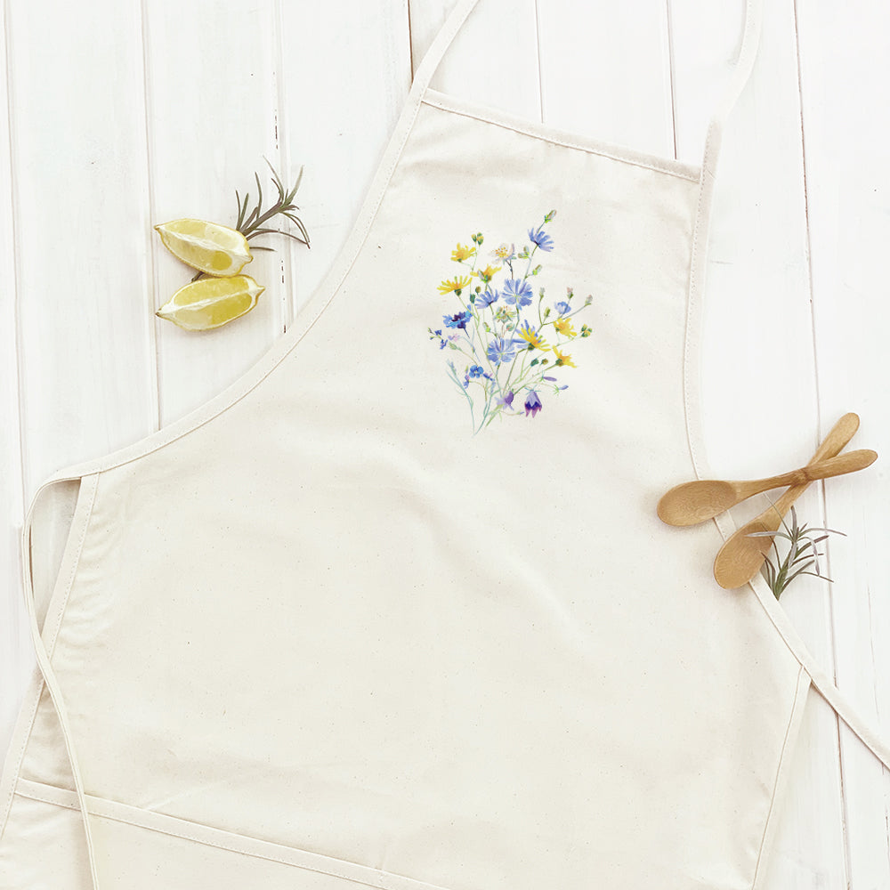 A stylish women's apron featuring a vibrant yellow and purple floral design, made from durable cotton canvas with a divided front pocket.