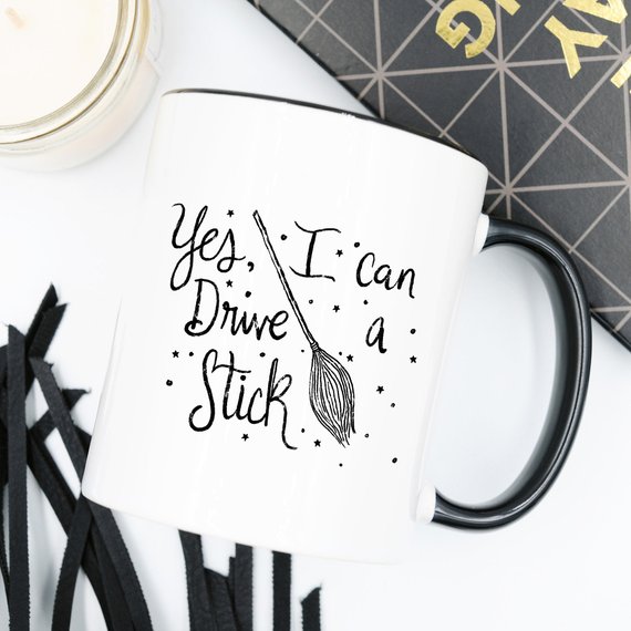 A humorous coffee mug featuring the phrase 'Yes I Can Drive A Stick', perfect for Halloween and coffee lovers.