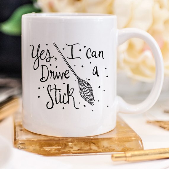 A humorous coffee mug featuring the phrase 'Yes I Can Drive A Stick', perfect for Halloween and coffee lovers.