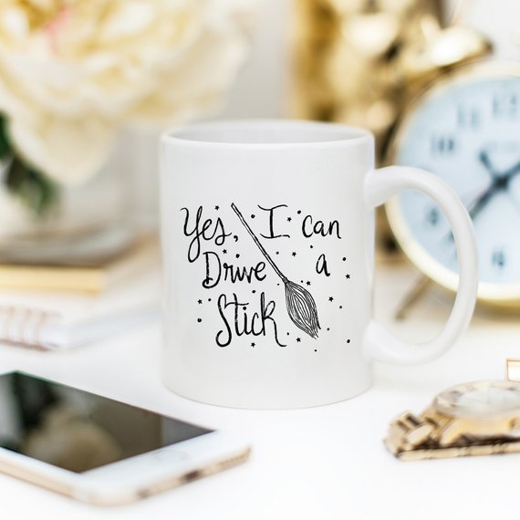 A humorous coffee mug featuring the phrase 'Yes I Can Drive A Stick', perfect for Halloween and coffee lovers.