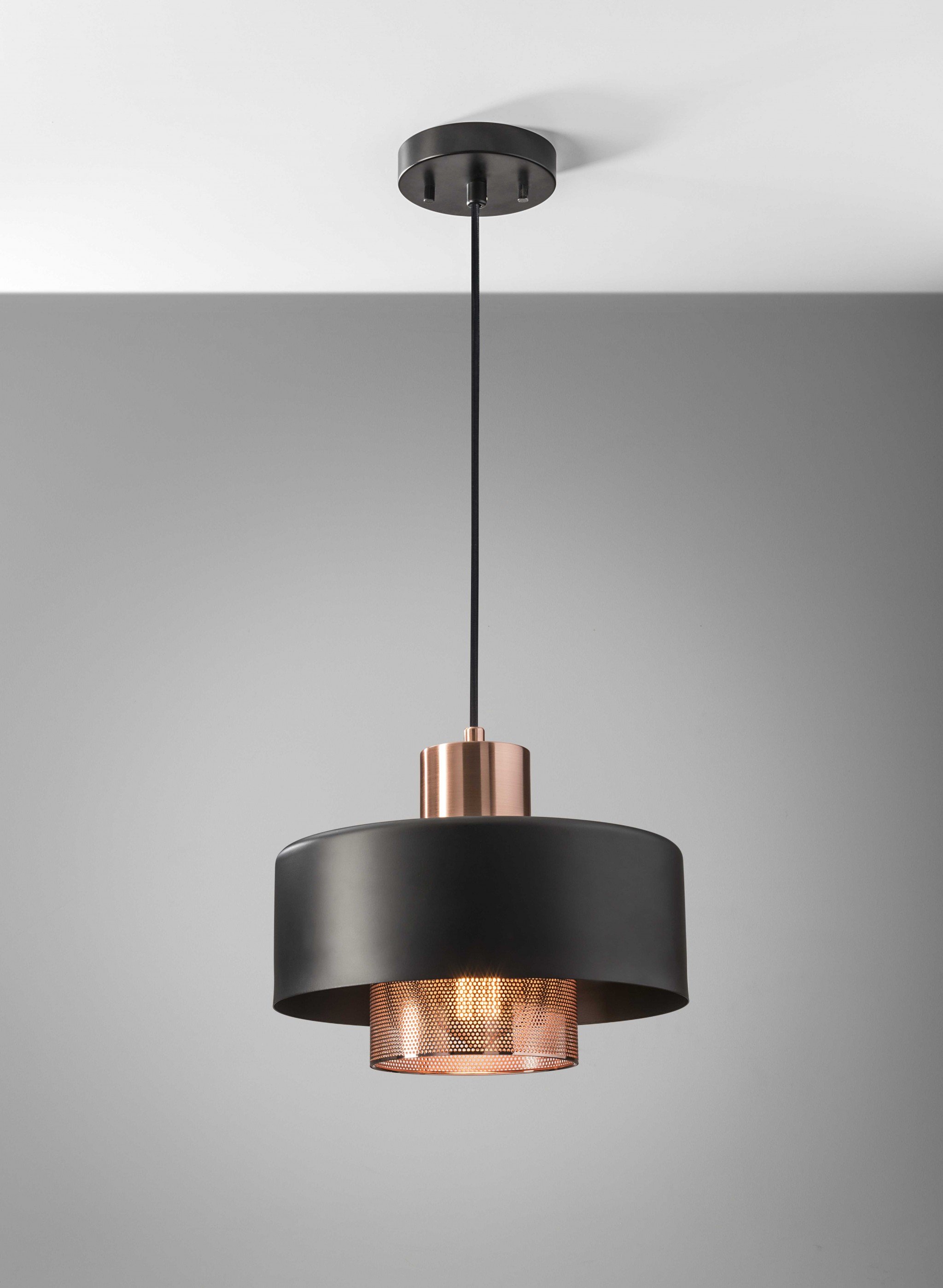 A stylish 11.5" X 11.5" X 9" copper metal pendant light with a perforated inner shade, showcasing warm ambient lighting.