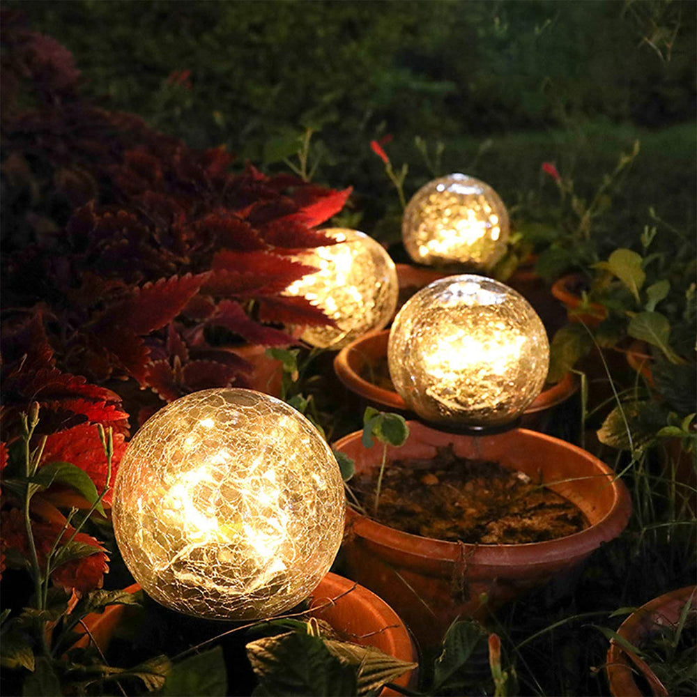 Two solar lights with cracked glass ball design illuminating a garden path at night, showcasing warm LED light patterns.