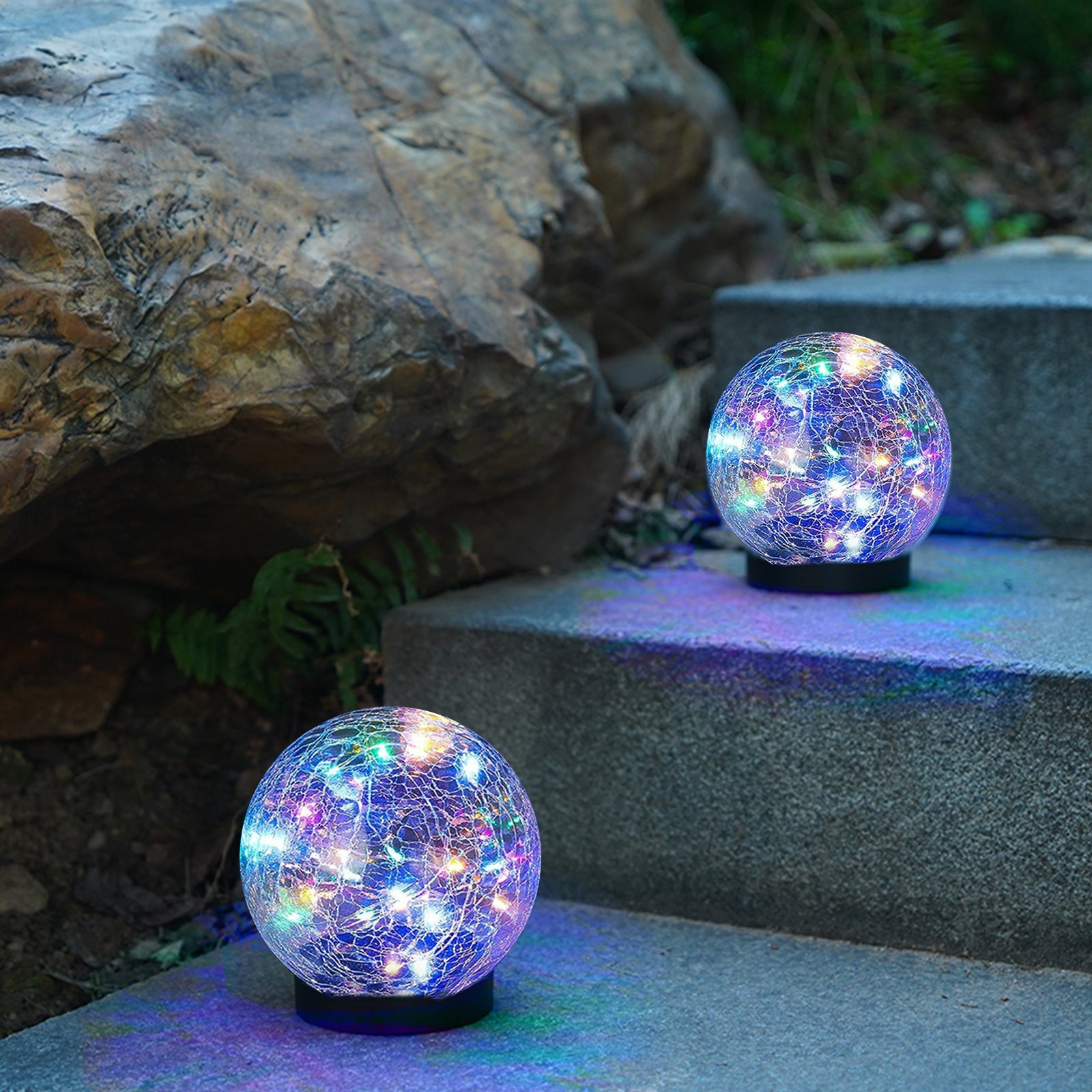 Two solar lights with cracked glass ball design illuminating a garden path at night, showcasing warm LED light patterns.