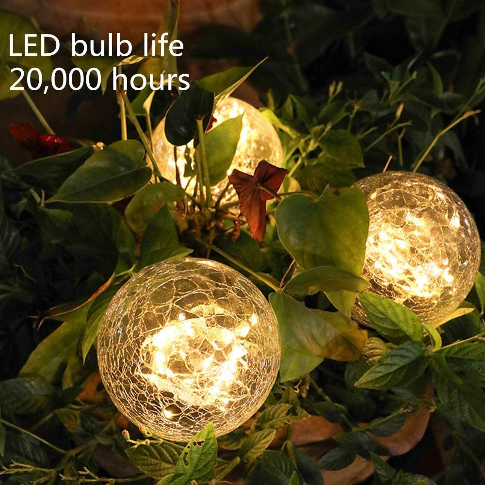 Two solar lights with cracked glass ball design illuminating a garden path at night, showcasing warm LED light patterns.