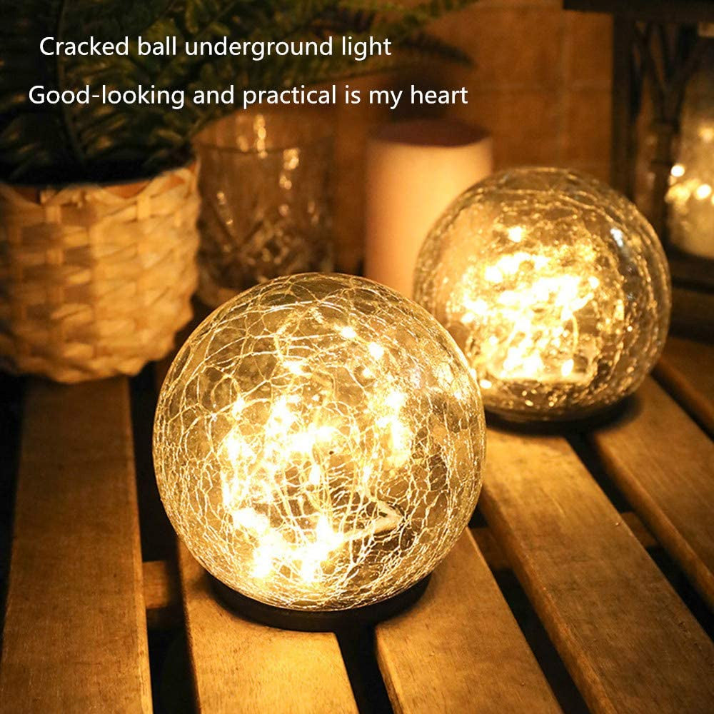 Two solar lights with cracked glass ball design illuminating a garden path at night, showcasing warm LED light patterns.