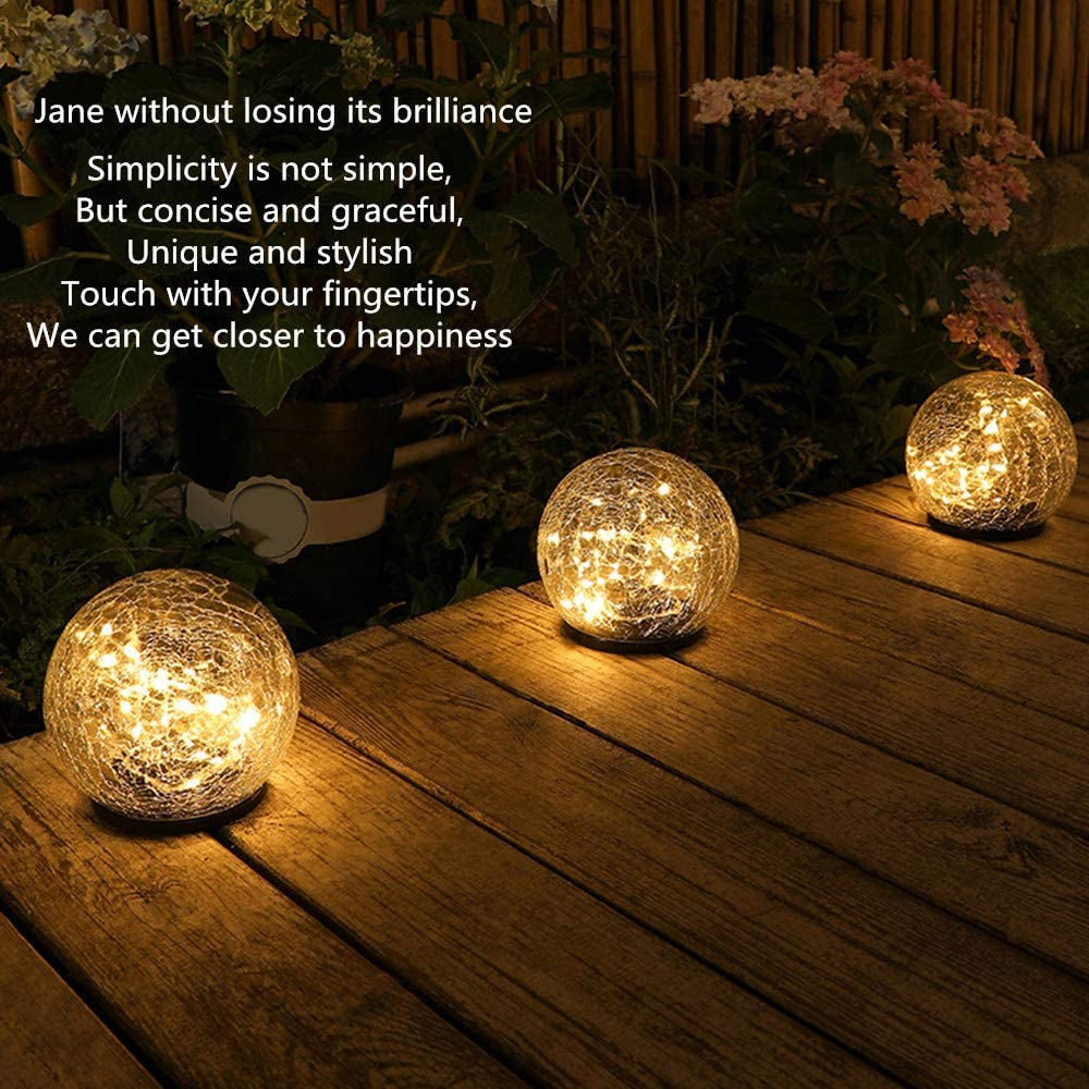 Two solar lights with cracked glass ball design illuminating a garden path at night, showcasing warm LED light patterns.