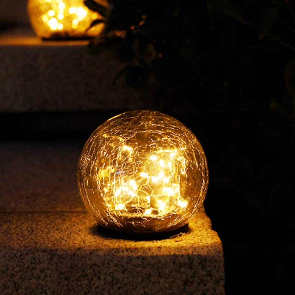 Two solar lights with cracked glass ball design illuminating a garden path at night, showcasing warm LED light patterns.