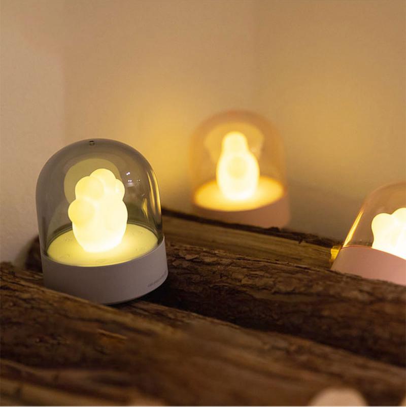 A cute cat paw-shaped night light with soft glowing light and a music box feature, perfect for home decor.