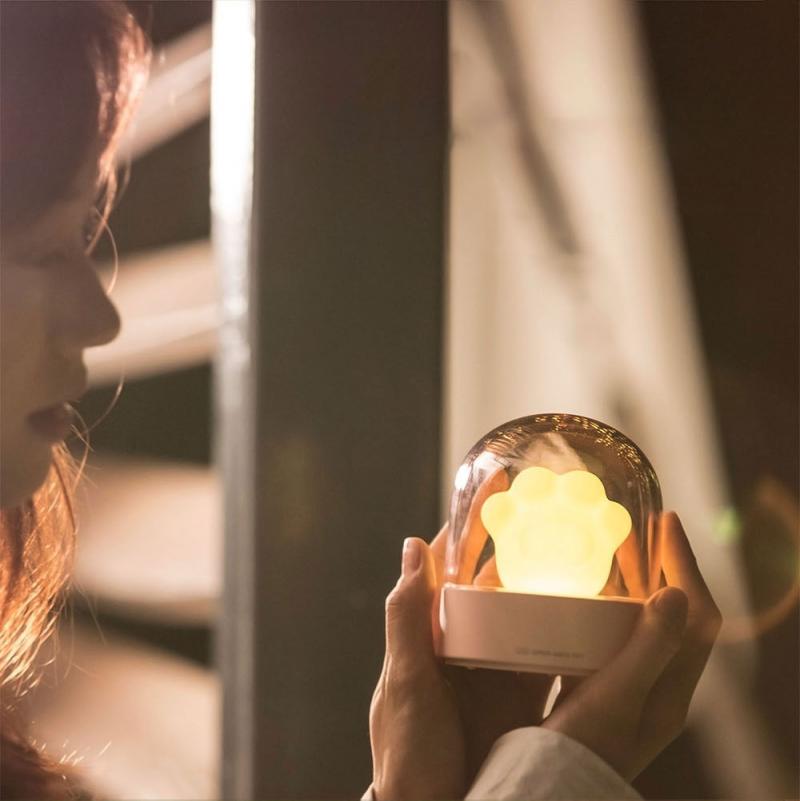 A cute cat paw-shaped night light with soft glowing light and a music box feature, perfect for home decor.