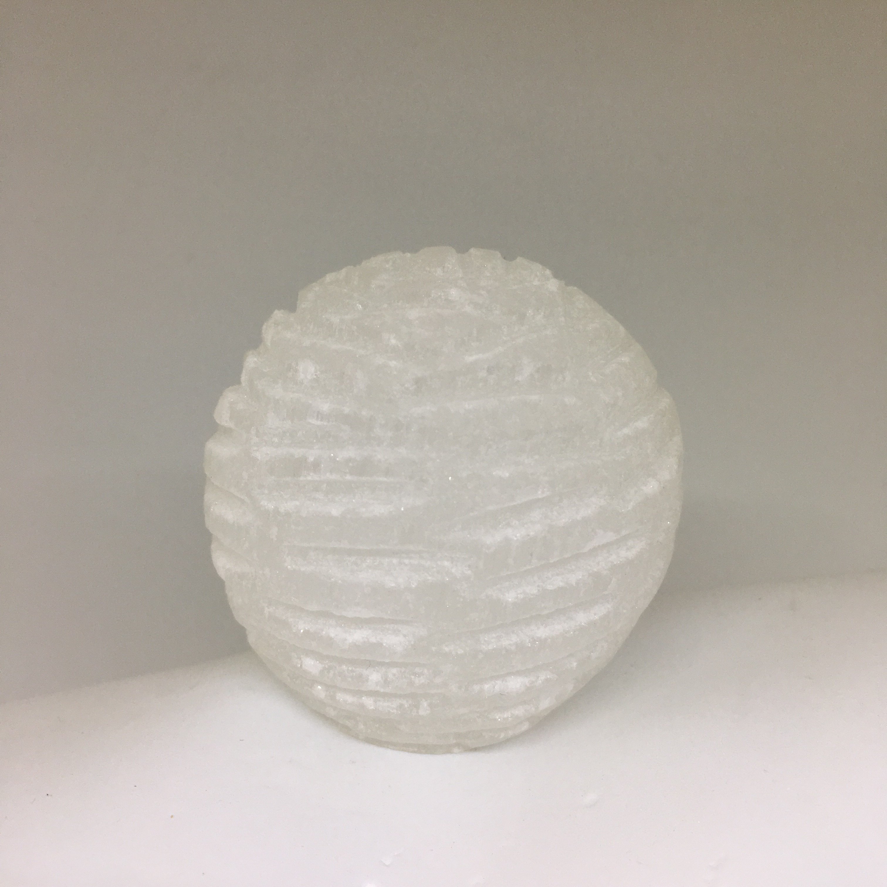 A beautifully crafted Selenite Bubble Lamp with a warm yellow LED flame, showcasing its unique hand-cut design by Moroccan artisans.