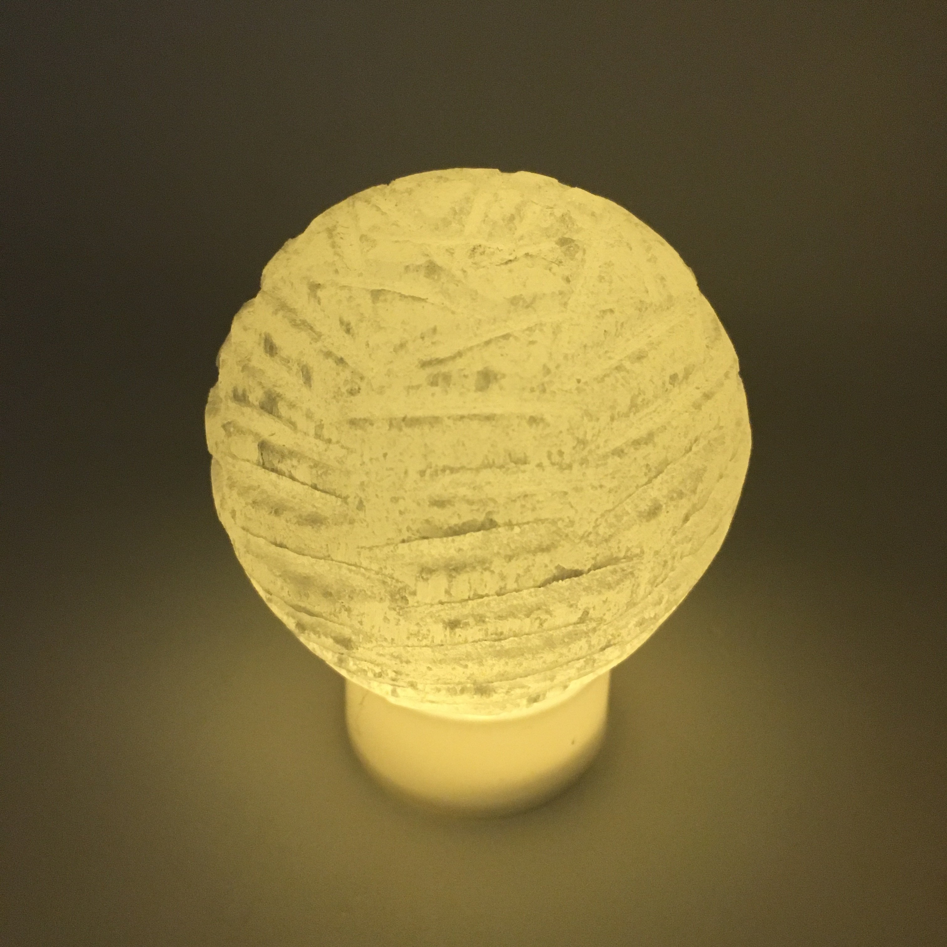 A beautifully crafted Selenite Bubble Lamp with a warm yellow LED flame, showcasing its unique hand-cut design by Moroccan artisans.