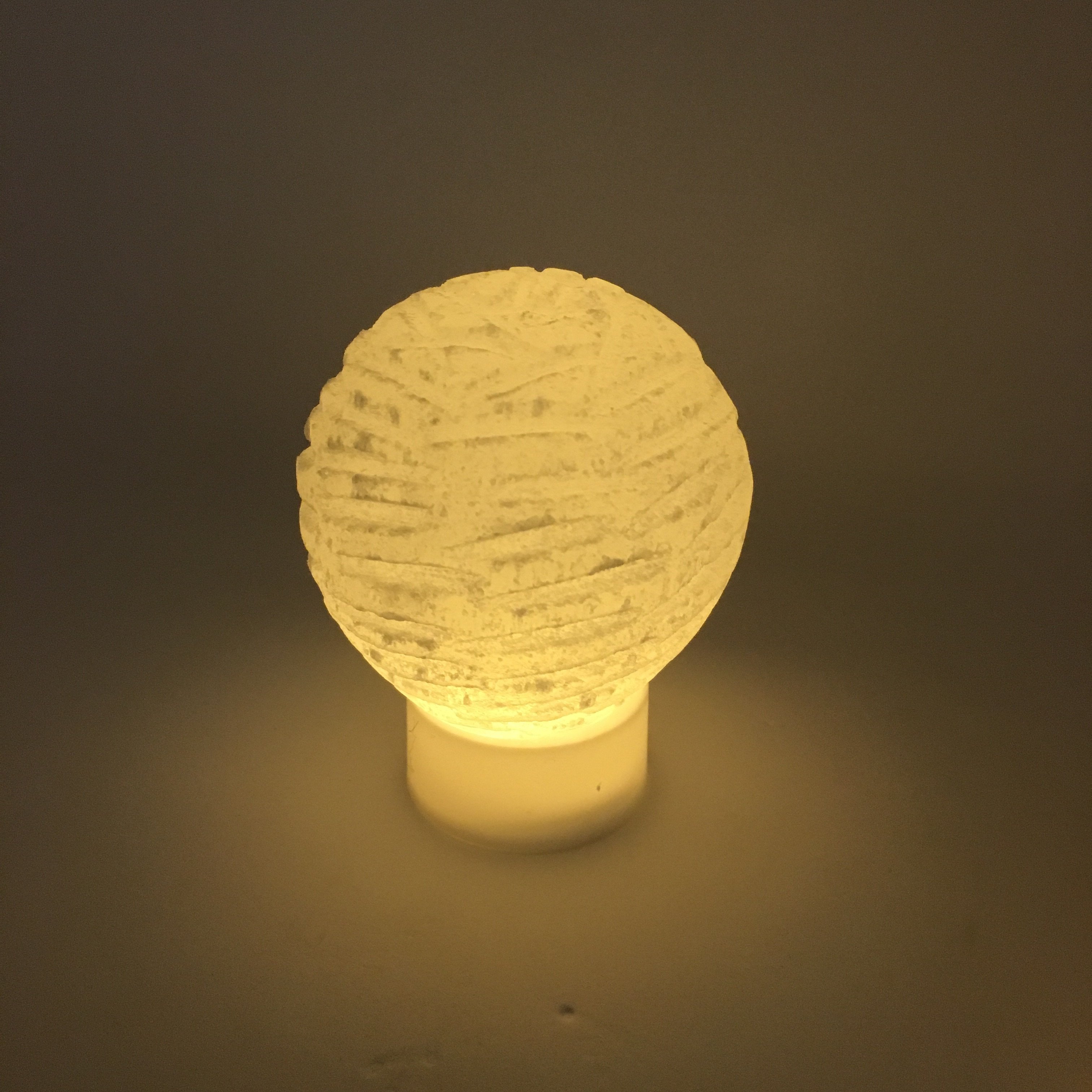 A beautifully crafted Selenite Bubble Lamp with a warm yellow LED flame, showcasing its unique hand-cut design by Moroccan artisans.