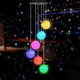 Colorful Solar Crystal Ball Wind Chime Light hanging in a garden, showcasing its vibrant LED lights and glassy design.