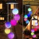 Colorful Solar Crystal Ball Wind Chime Light hanging in a garden, showcasing its vibrant LED lights and glassy design.