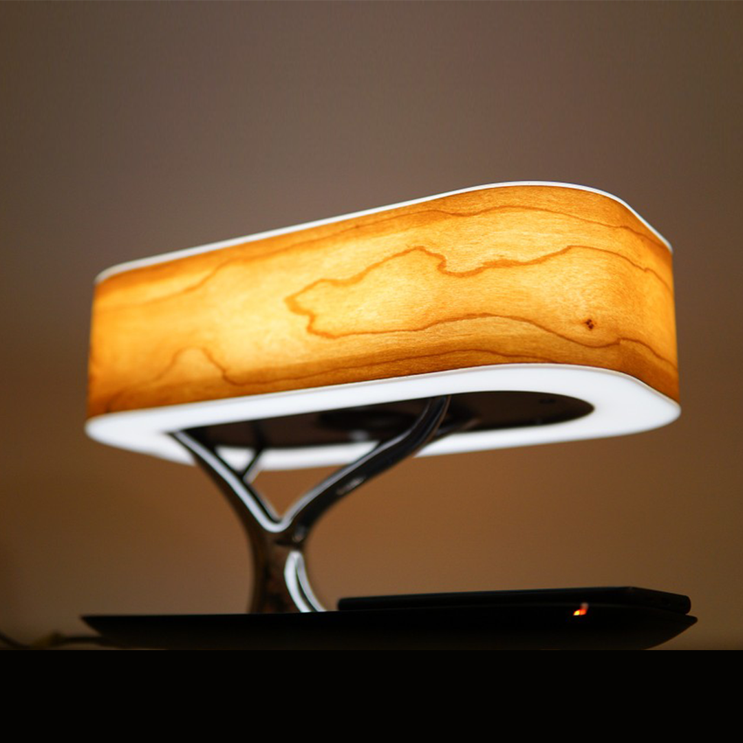 The Tree of Light bedside lamp featuring a cherry wood shade, touch controls, wireless charging pad, and Bluetooth speaker.