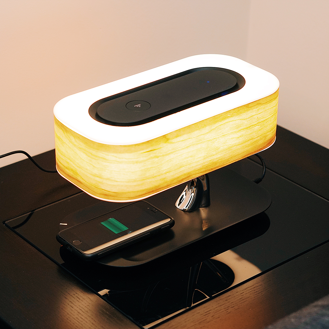 The Tree of Light bedside lamp featuring a cherry wood shade, touch controls, wireless charging pad, and Bluetooth speaker.