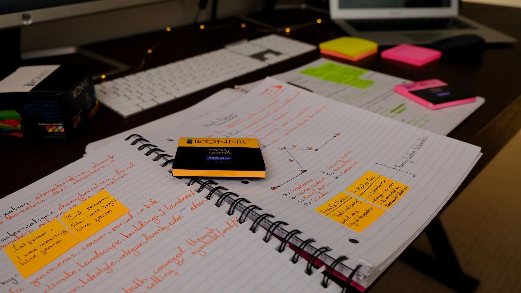 A vibrant assortment of 12 pack 3x3 self-stick sticky notes in various bright colors including pink, blue, yellow, green, orange, magenta, and purple, displayed on a clean desk.