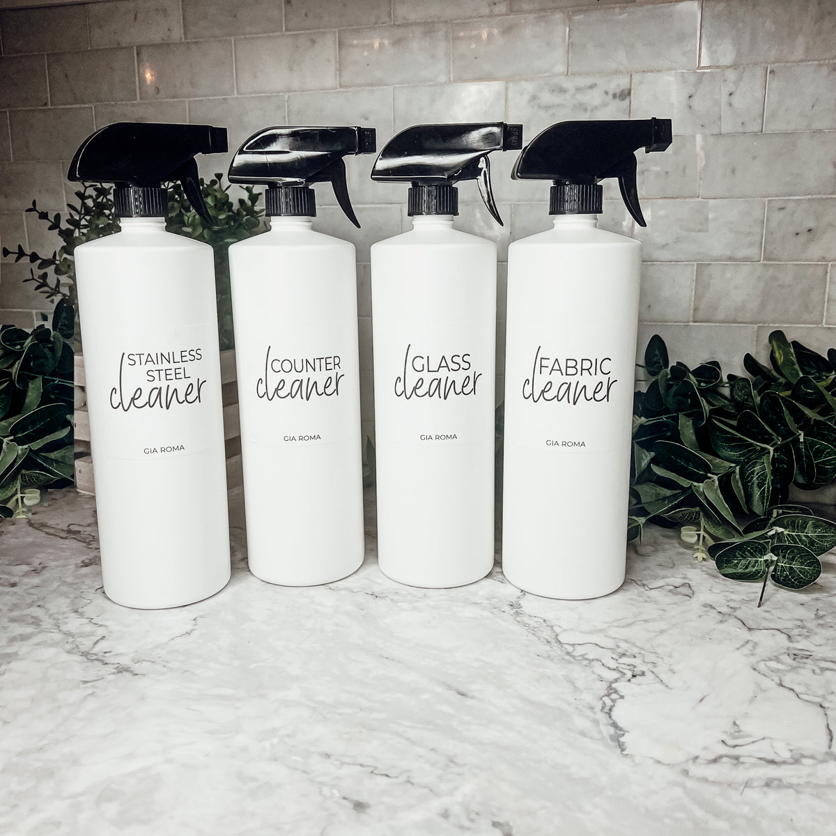 A set of 32oz white plastic cleaning bottles with spray pumps, showcasing their sleek design and customizable waterproof labels.