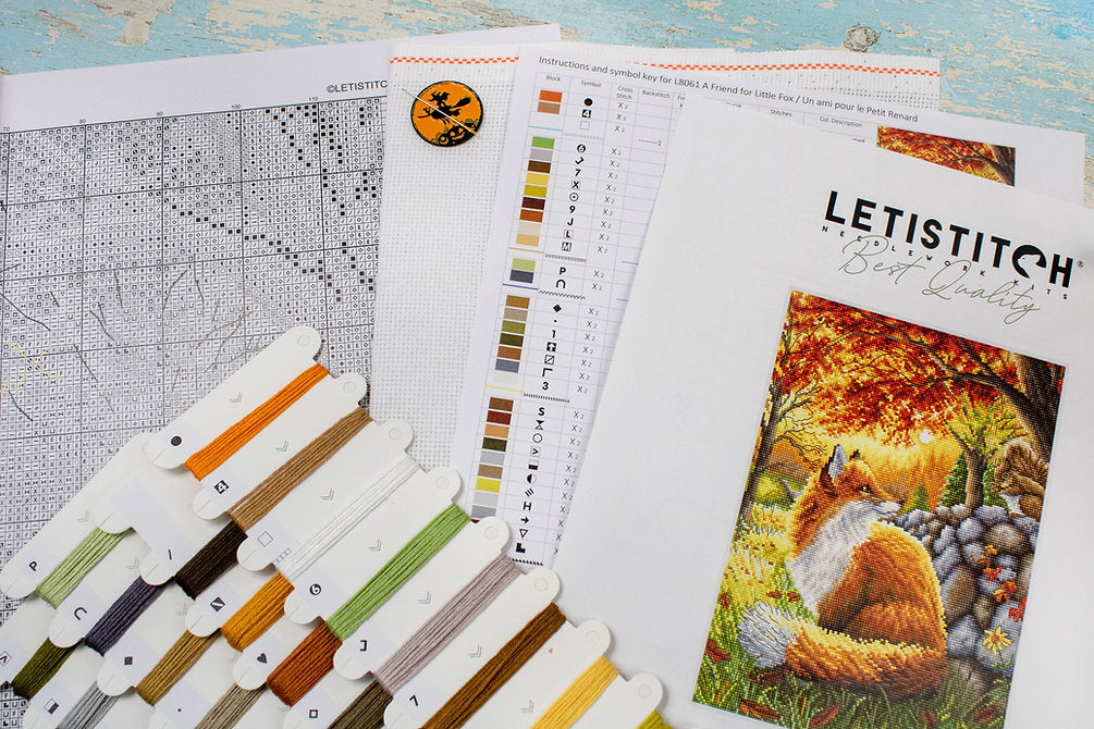 A counted cross stitch kit featuring a friendly fox design, including Aida canvas, colorful threads, and a needle.