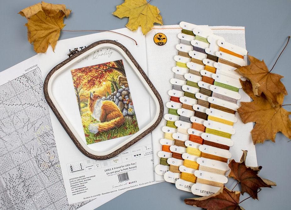 A counted cross stitch kit featuring a friendly fox design, including Aida canvas, colorful threads, and a needle.