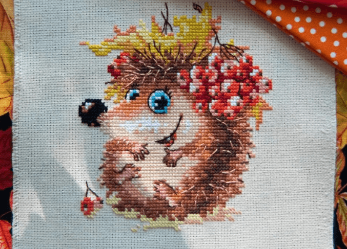 Autumn Hedgehog 0-75 Counted Cross-Stitch Kit featuring colorful threads, white aida fabric, and embroidery needles.