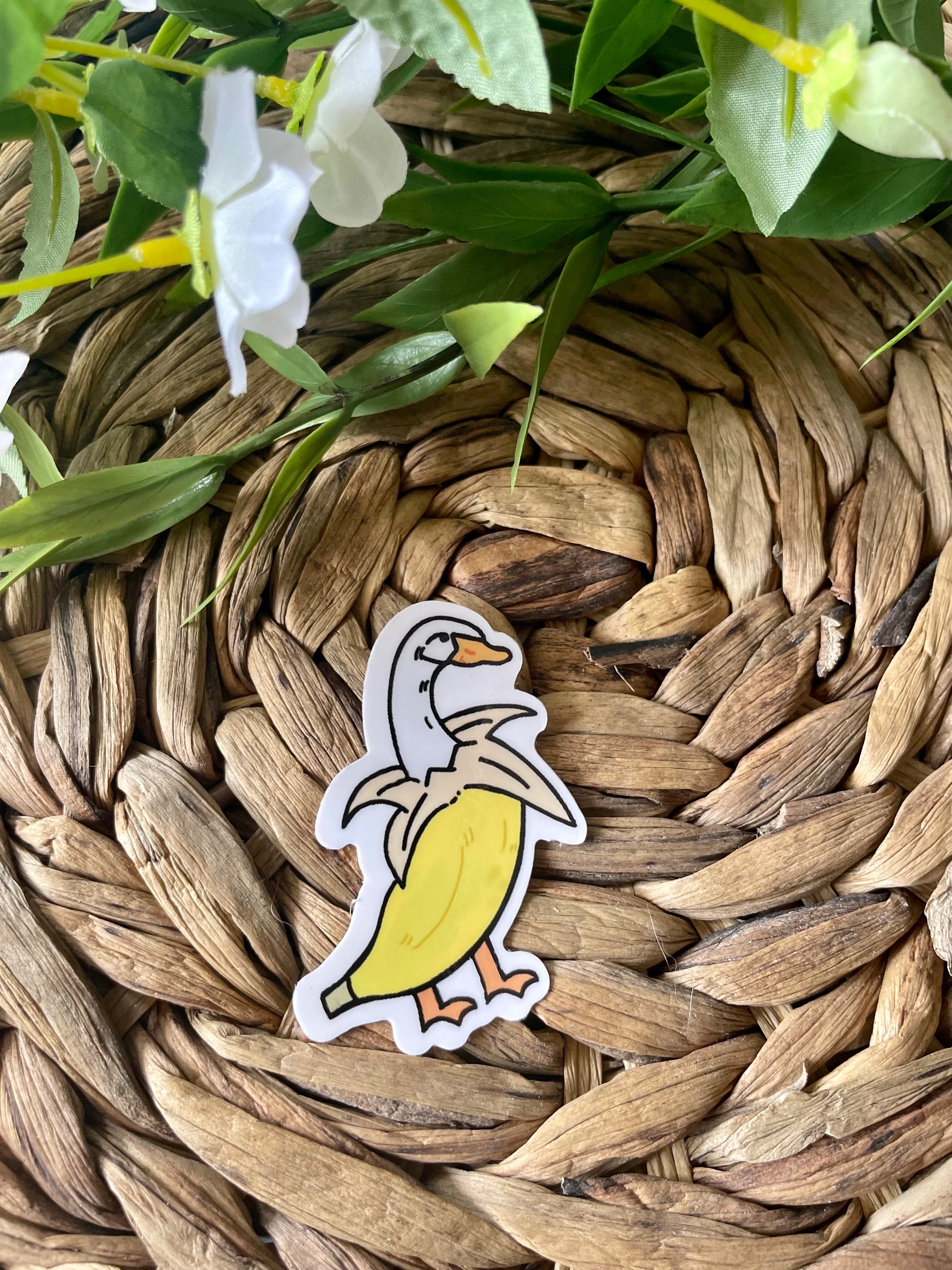 A cute banana duck sticker featuring a whimsical design, available in white and purple options, perfect for personalizing items.