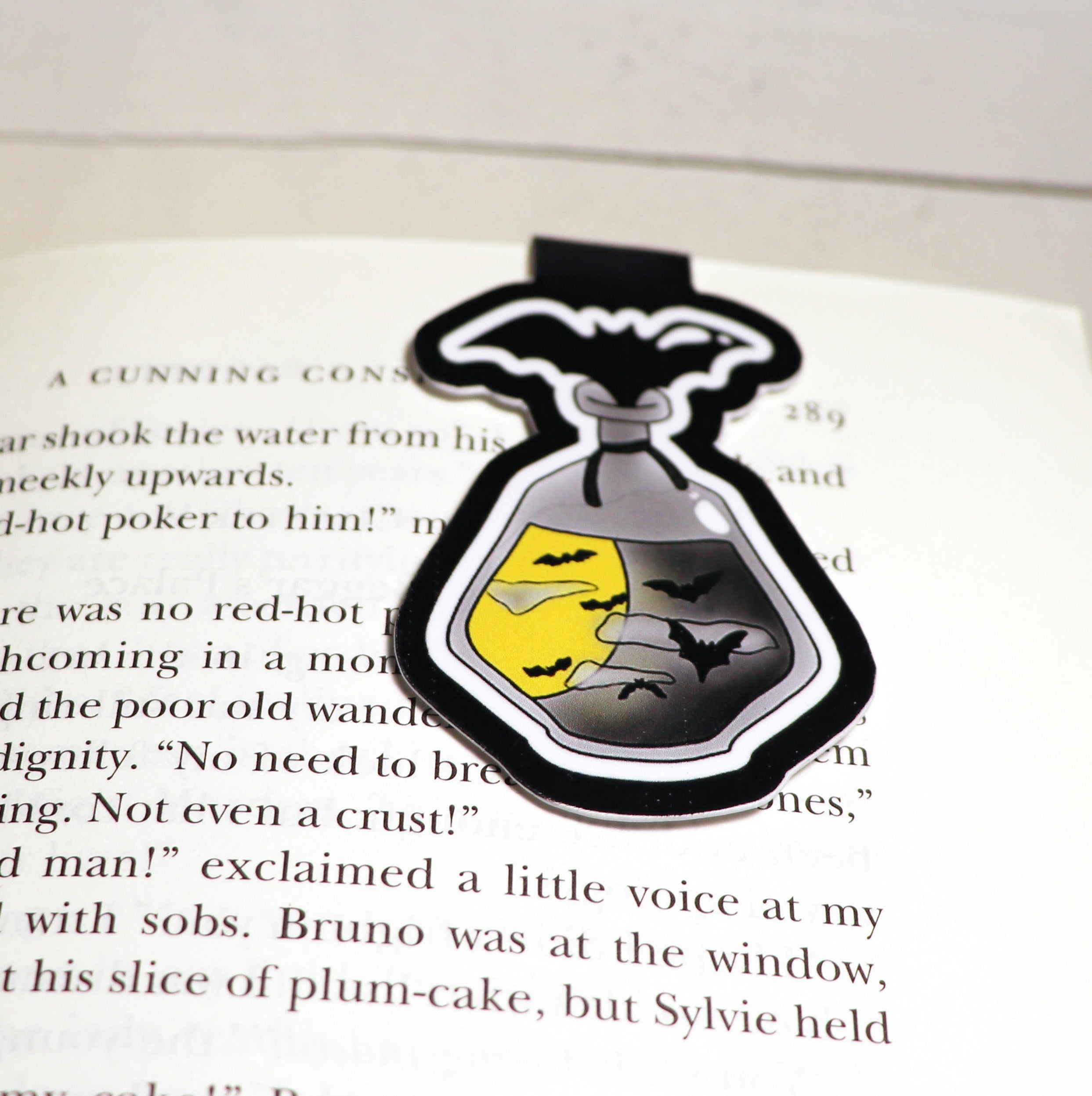 A whimsical Bat Potion Bottle Bookmark featuring a double-sided design with vibrant colors, strong magnets, and a durable finish, perfect for avid readers.