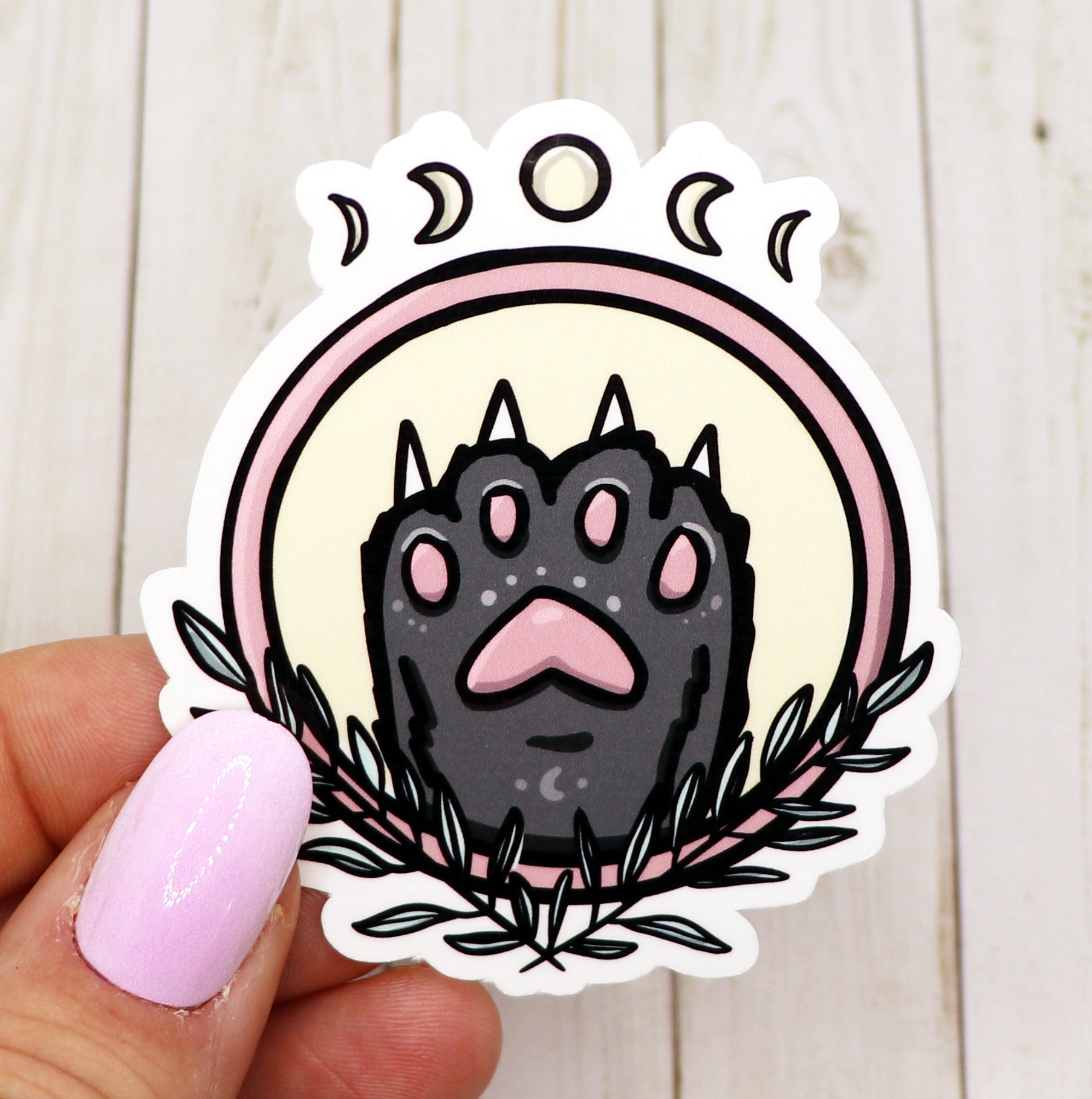 A cute black cat paw vinyl sticker on a white background, showcasing its glossy finish and intricate details.