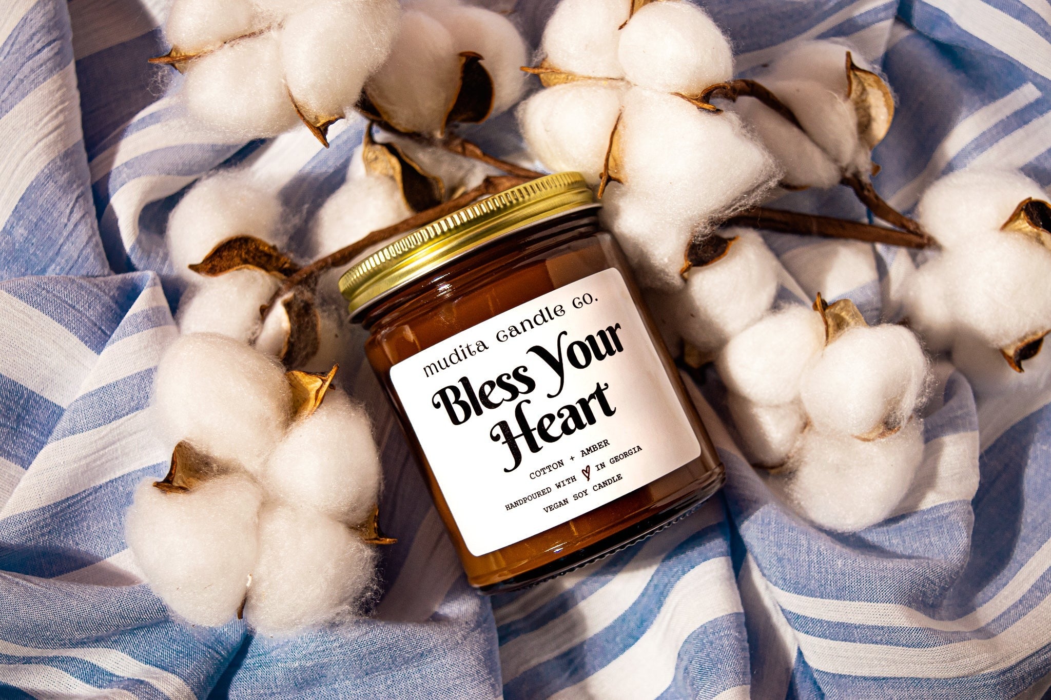 Bless Your Heart Cotton Amber Soy Candle in a reusable amber glass jar with a gold lid, showcasing its elegant design and inviting aroma.