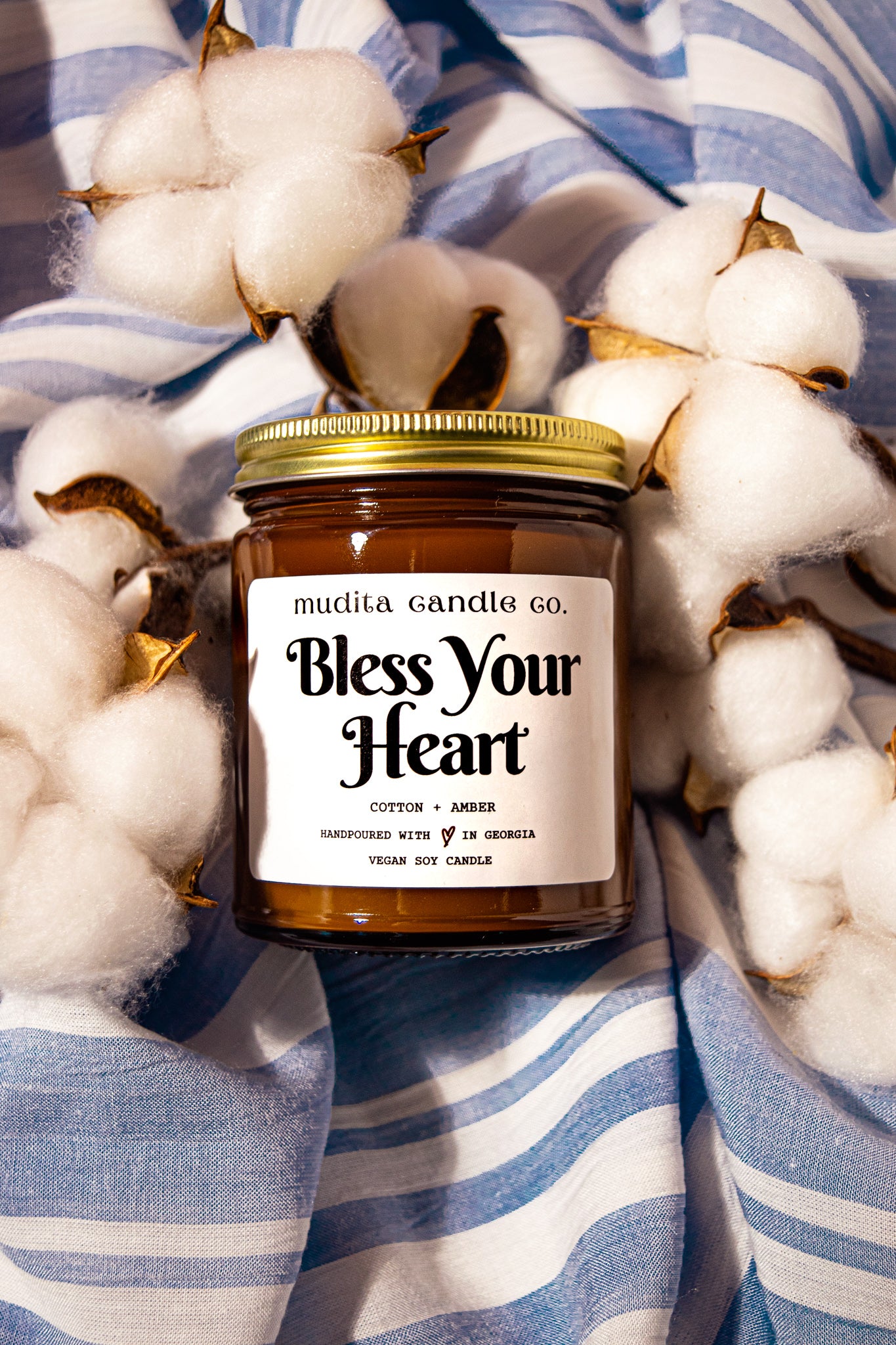 Bless Your Heart Cotton Amber Soy Candle in a reusable amber glass jar with a gold lid, showcasing its elegant design and inviting aroma.