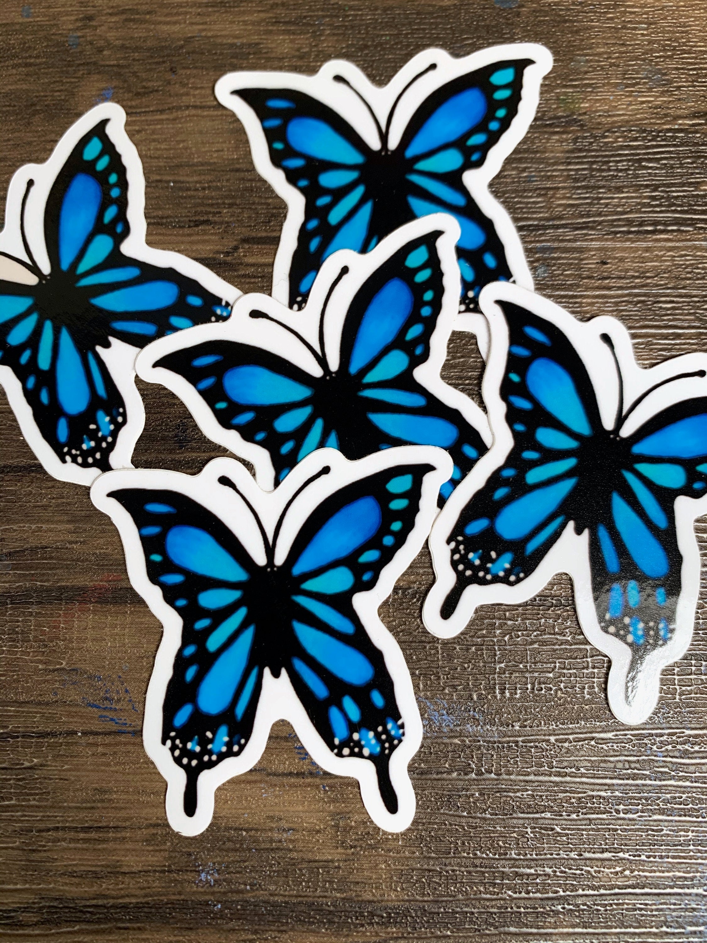 A vibrant blue butterfly sticker designed for customization, featuring intricate details and a glossy finish.